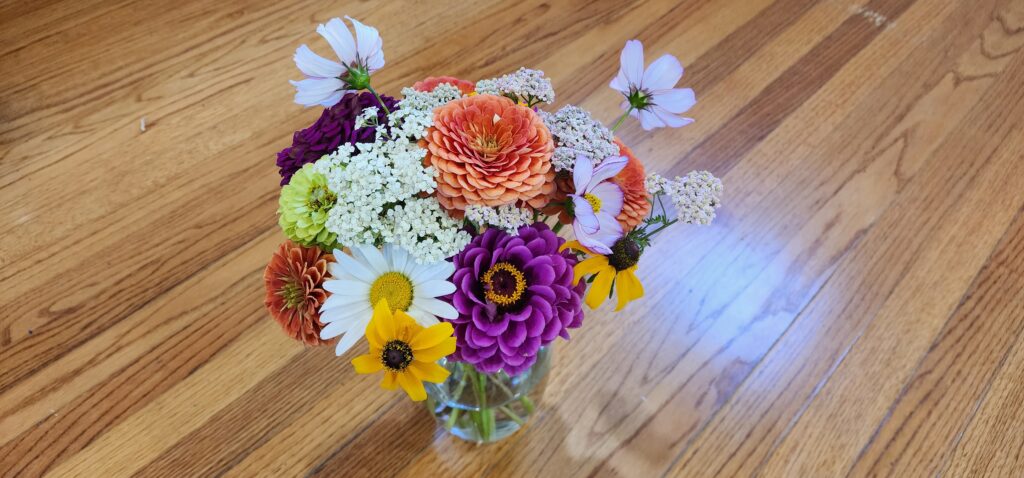 a flower bouquet filled with zinnias, daisies, yarrow and rudbeckia