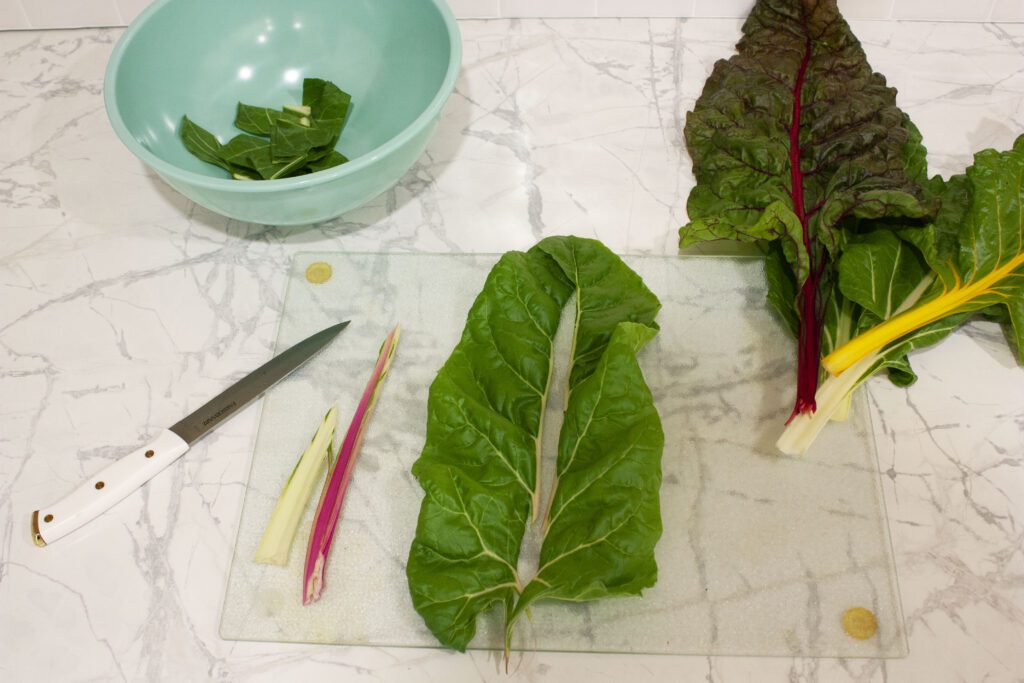 a swiss chard leaf is cut with the stem in the centre being removed
