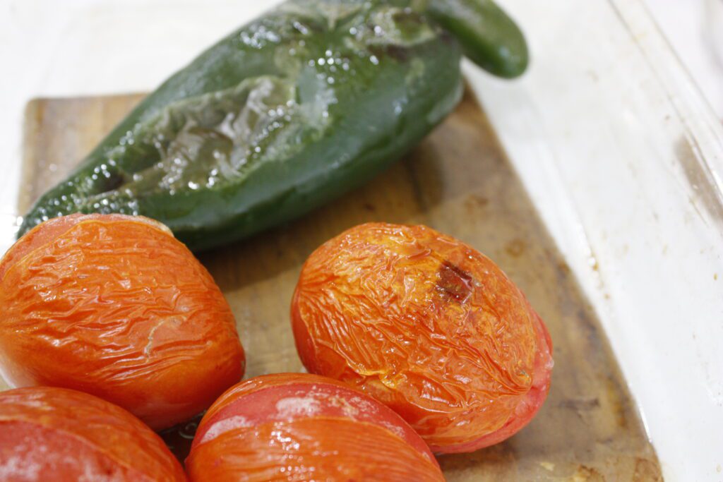 oven broiled peppers and tomatoes sit in a baking sheet
