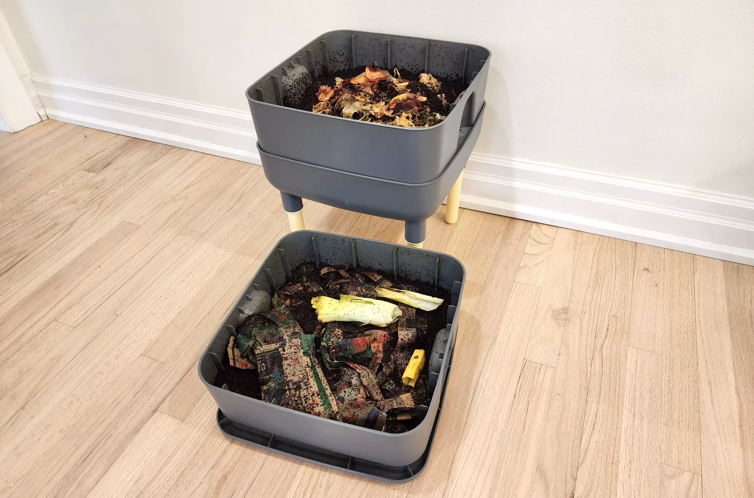 a worm tower is shown with two levels filled with worm castings, newspaper, and food